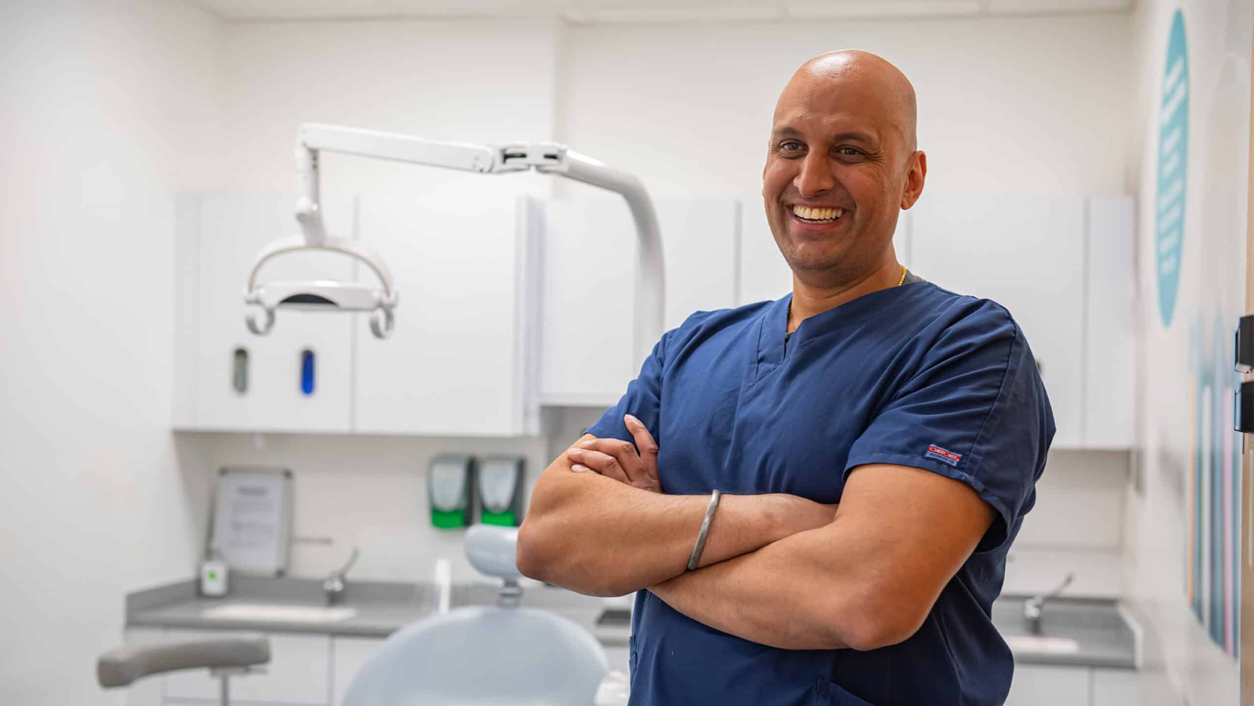 Dentist in blue scrubs smiling, representing our employer brand for mydentist
